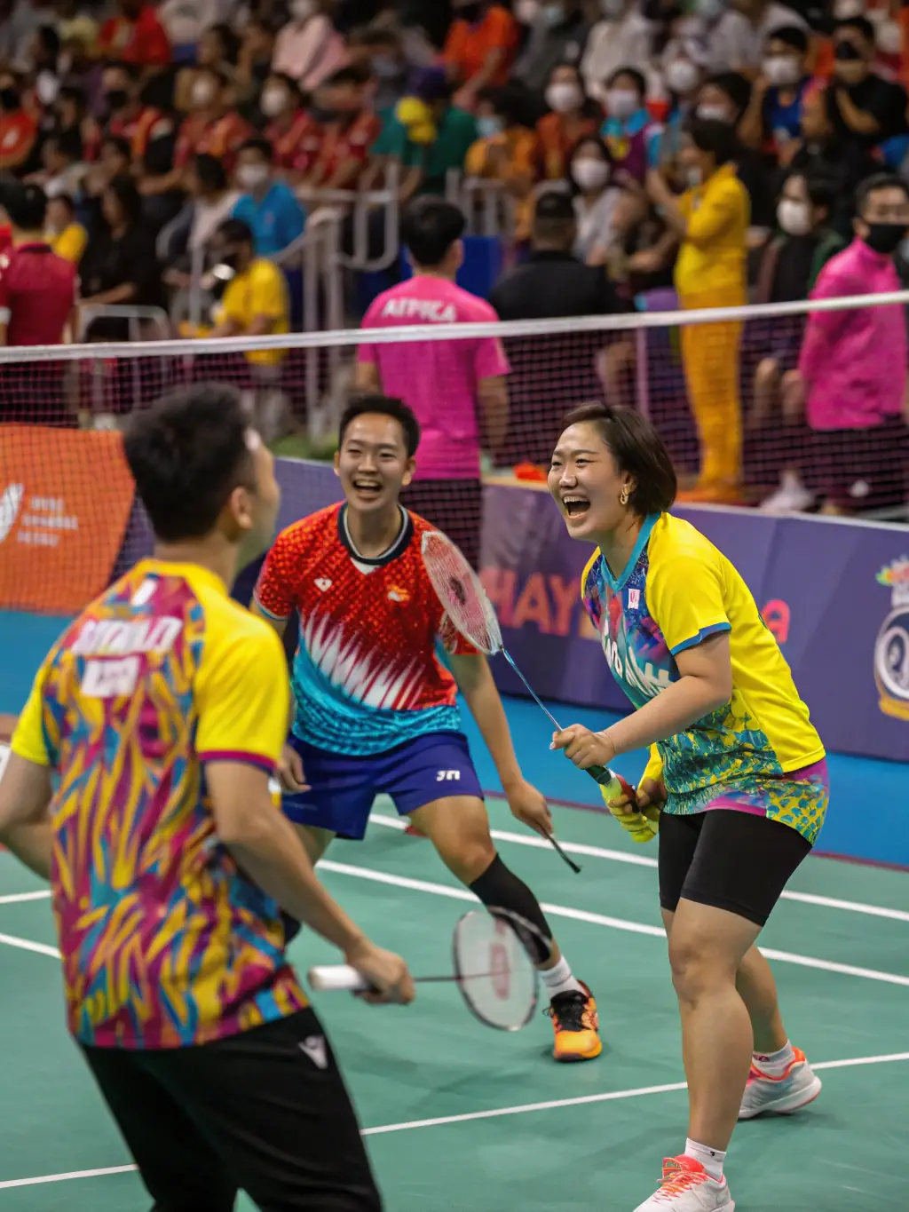 A group of young badminton players in their teens, laughing and high-fiving after a successful drill during a training session at the ROANNE BADMINTON CLUB (CBR42).