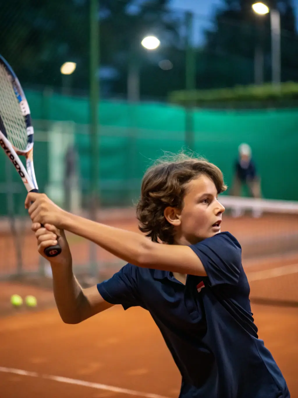A young badminton player, around 10 years old, intensely focused on hitting a shuttlecock during a practice match at the ROANNE BADMINTON CLUB (CBR42).